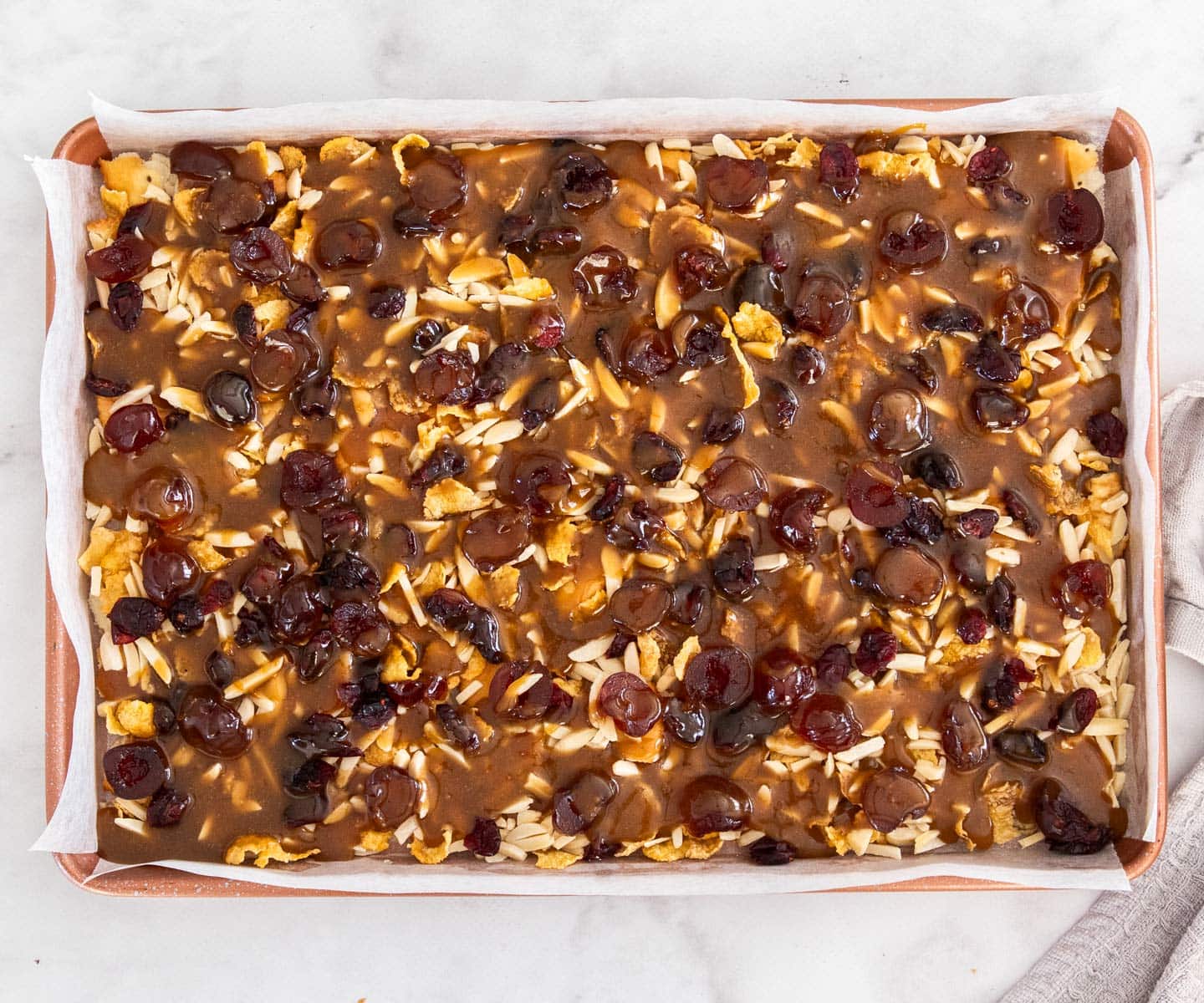 The toffee poured over the filling ingredients in the baking tray.