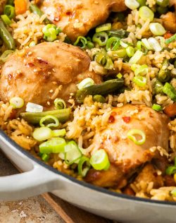 Closeup of the cooked chicken thighs nestled into rice and veggies.