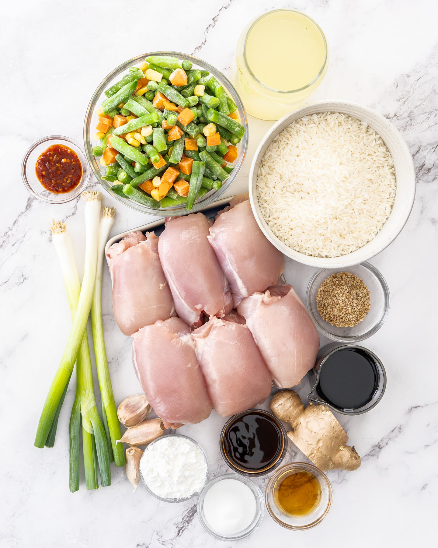 One Pan Baked Chicken and Rice Ingredients for chicken and rice bake on a marble surface.