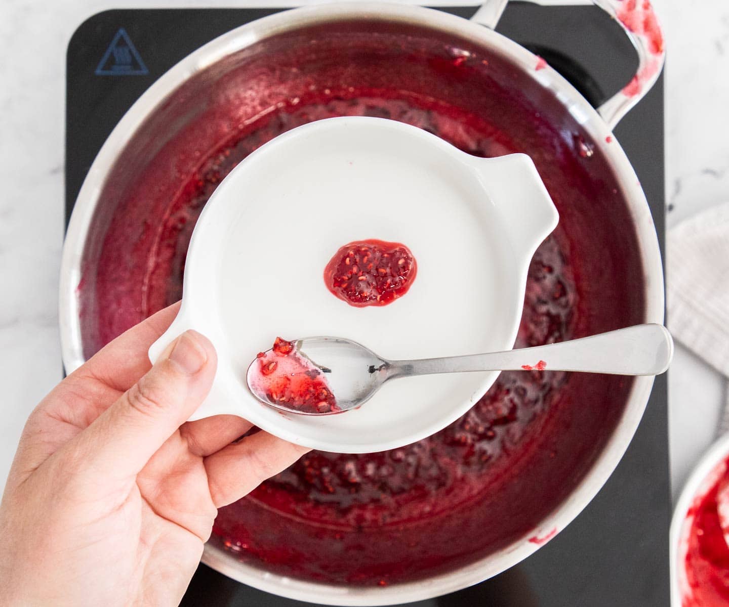 Easy Raspberry Jam A small scoop of raspberry jam on a saucer.