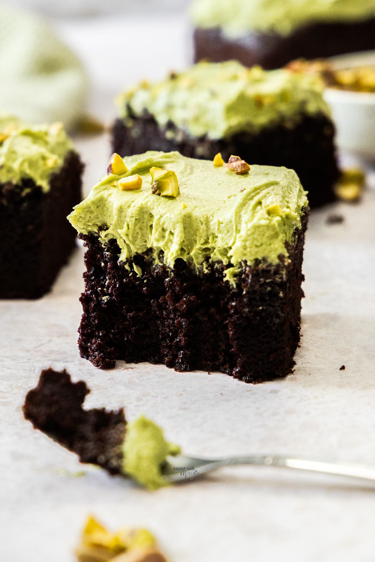 Pistachio Chocolate Snack Cake A square of pistachio chocolate cake with forkfuls cut away.