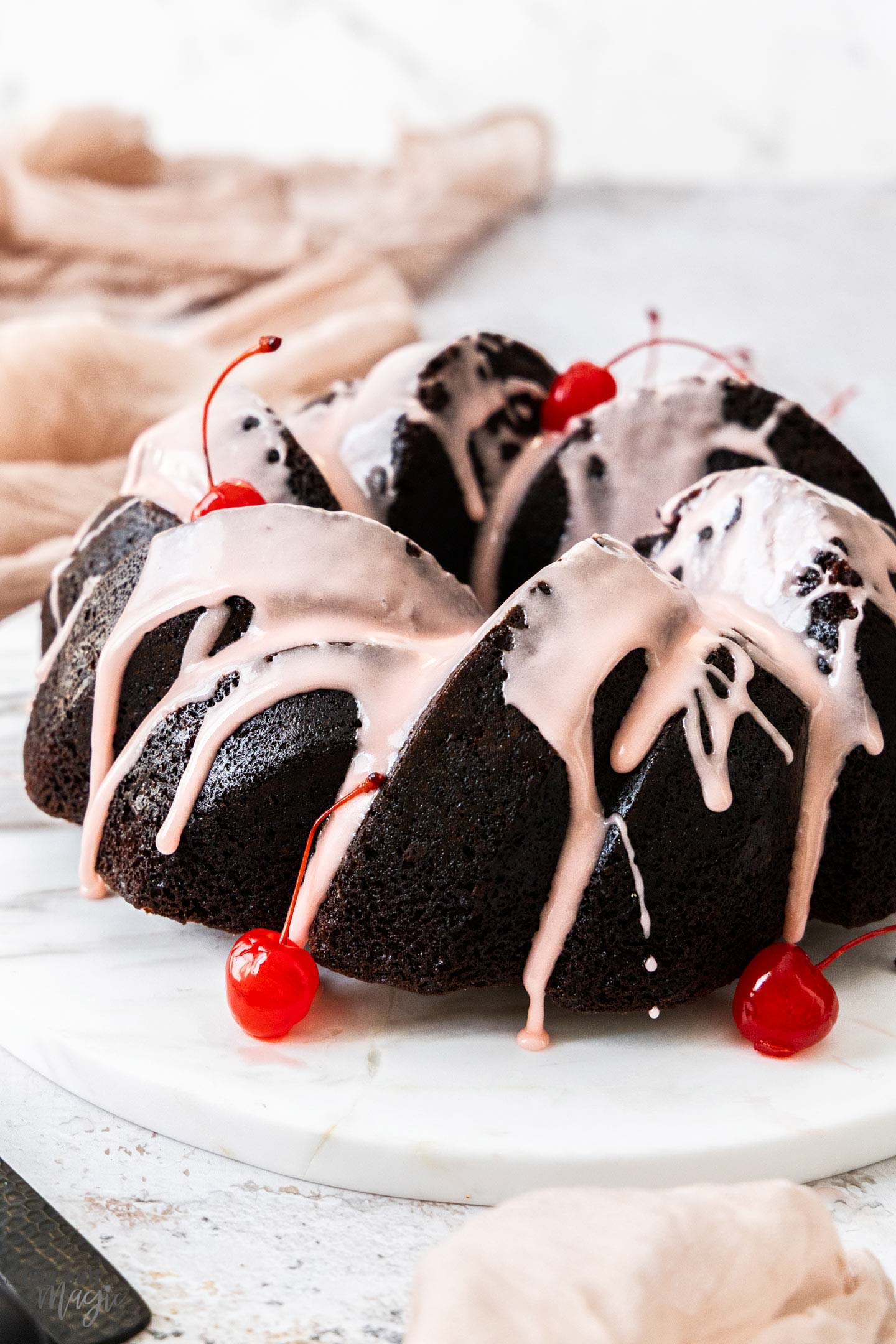 Cherry Chocolate Bundt Cake A whole chocolate cherry bundt cake on a marble platter.