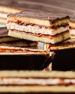 A finger of wagon wheel slice sitting on top of a pile of them.