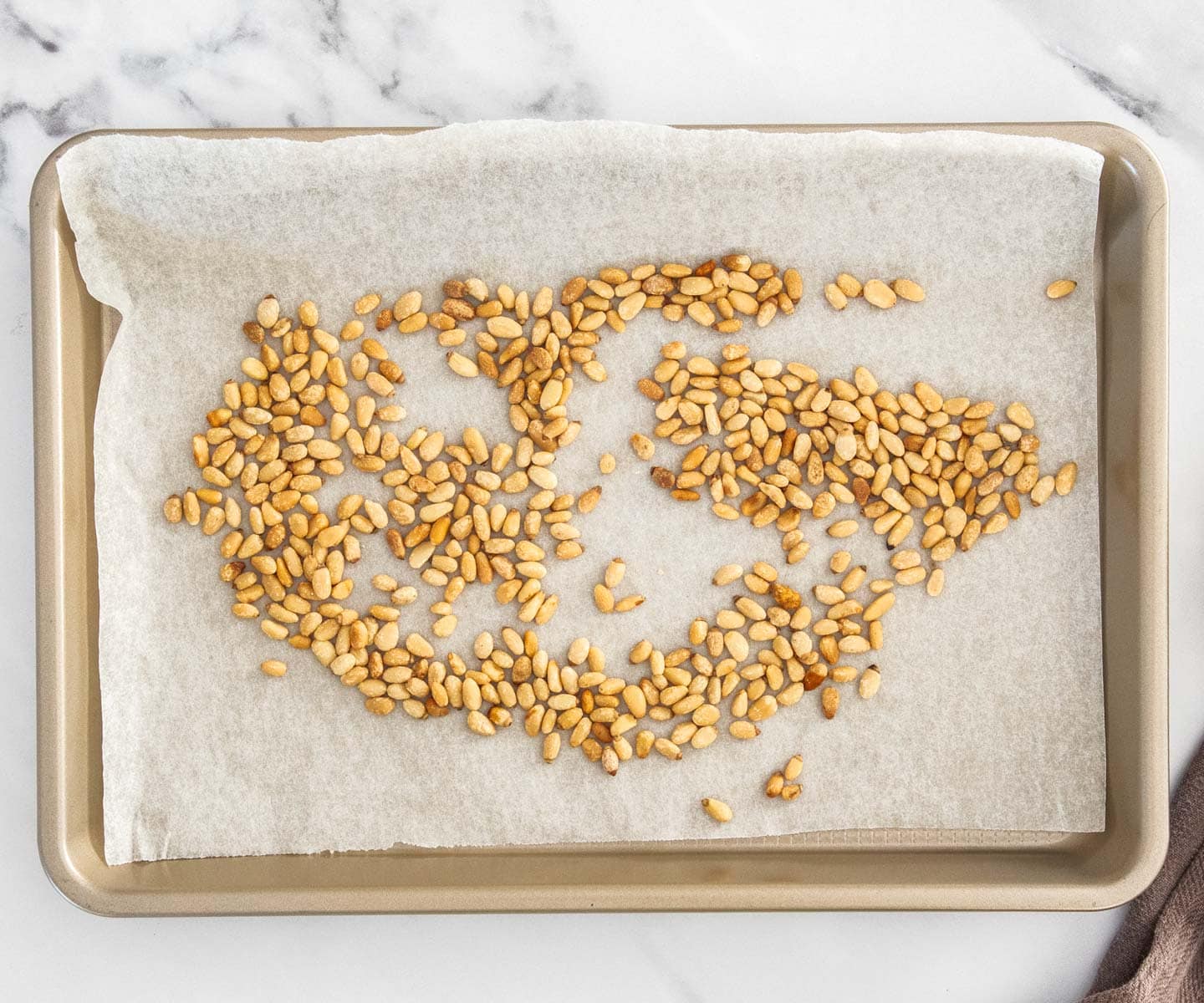 Sun-dried Tomato Pesto Pasta Toasted pine nuts on a baking tray.