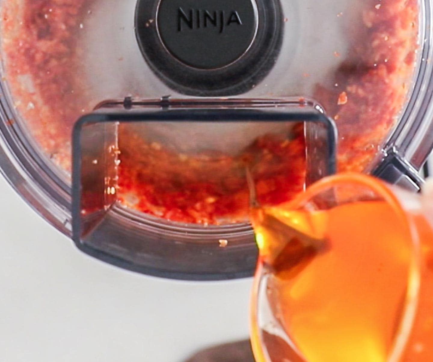 Sun-dried Tomato Pesto Pasta Pouring oil into a food processor.